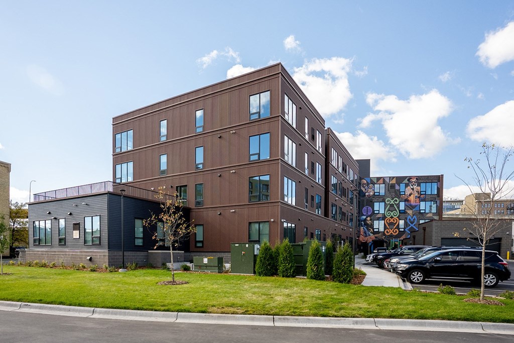 a brick building with a green lawn in front of a street