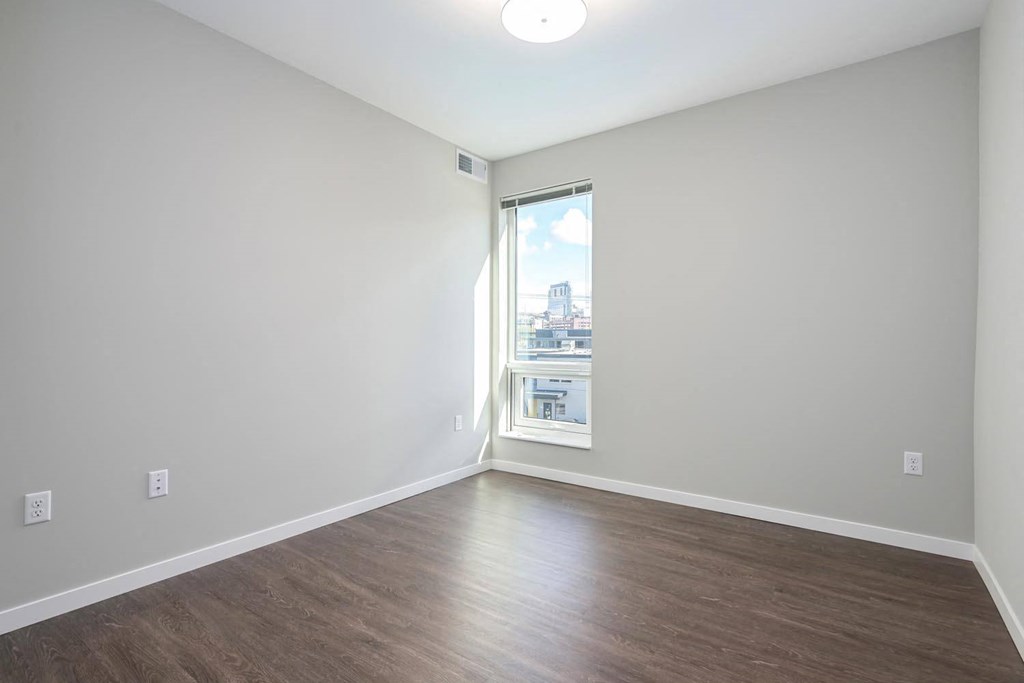 an empty living room with wood floors and a window