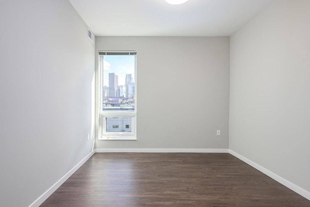room with a window and hardwood flooring and white walls