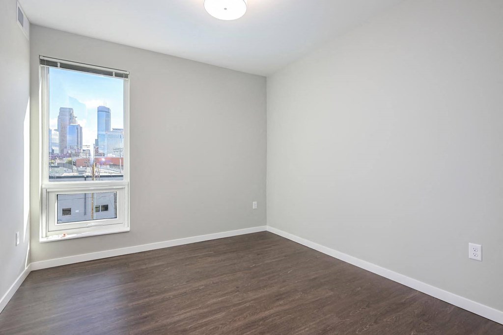 an empty room with a window and wood floors