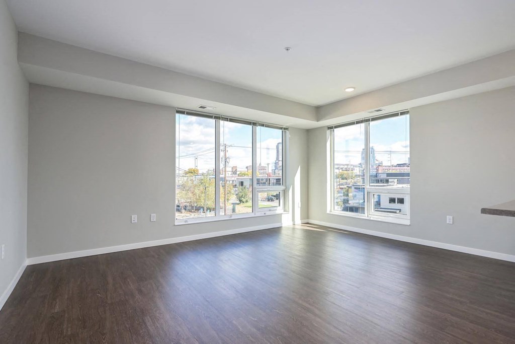 an empty living room with wood floors and large windows