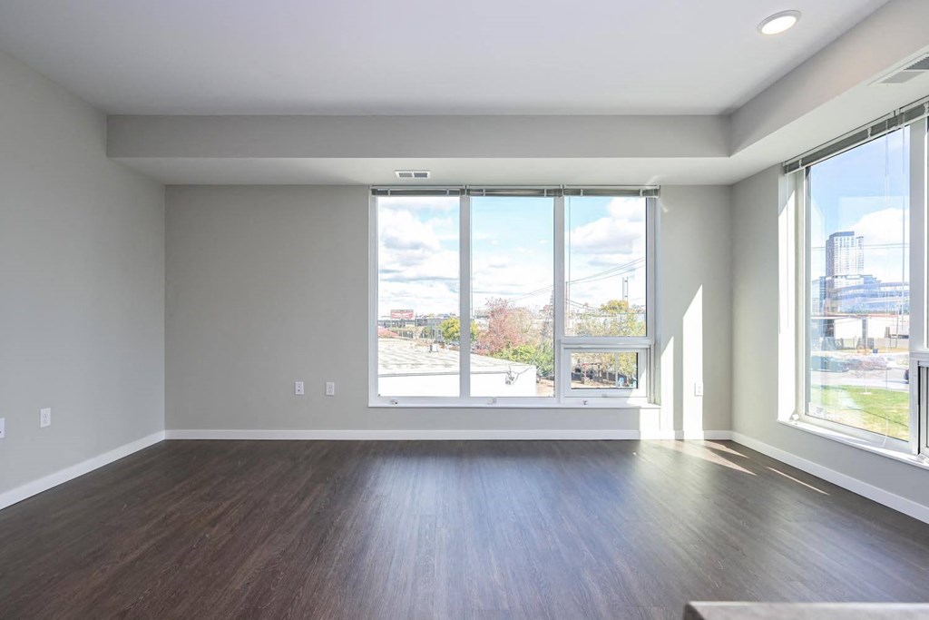 an empty living room with a large window and wood floors