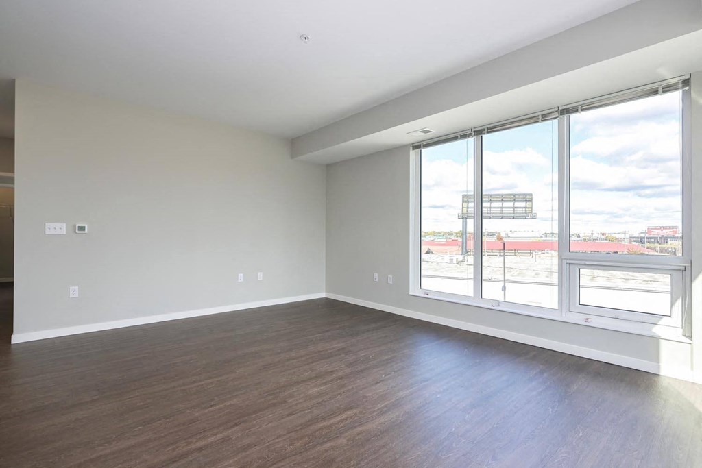 an empty living room with wood flooring and large windows