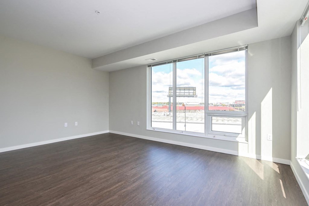 an empty living room with a large window and wood floors