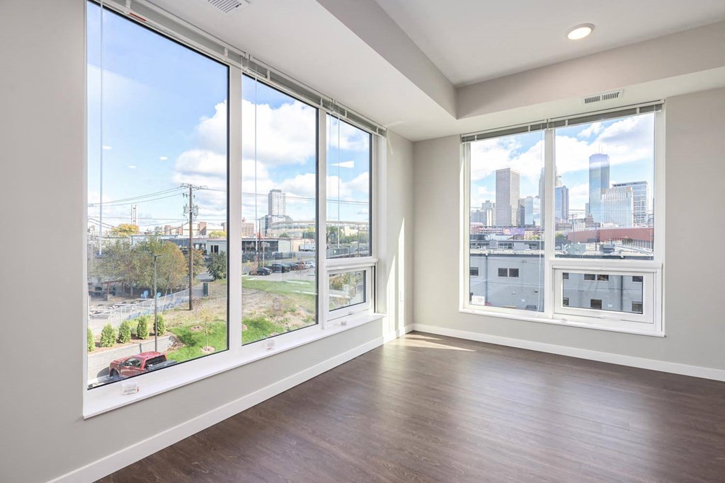 an empty living room with large windows and a city view