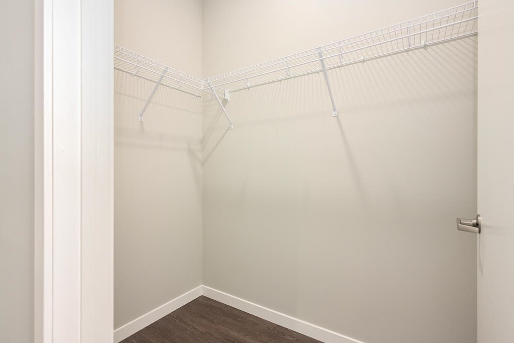 a walk in closet in a bedroom with white walls and