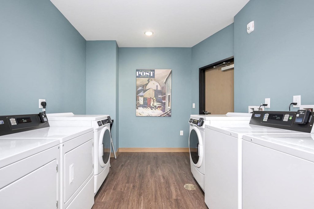 a laundry room with four washer and dryer machines