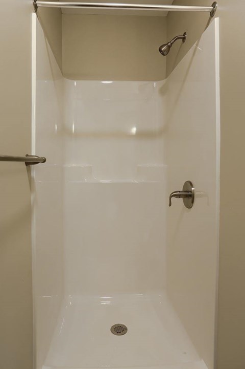 A white shower stall with a door and a shower head.