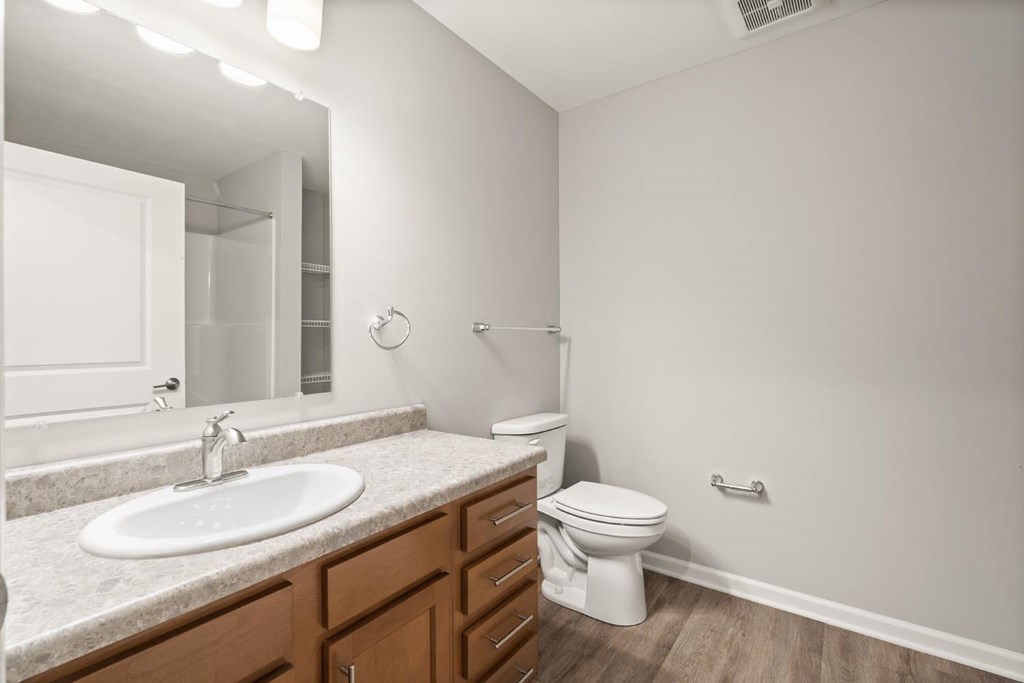 A white toilet sits in a bathroom with a sink and mirror.