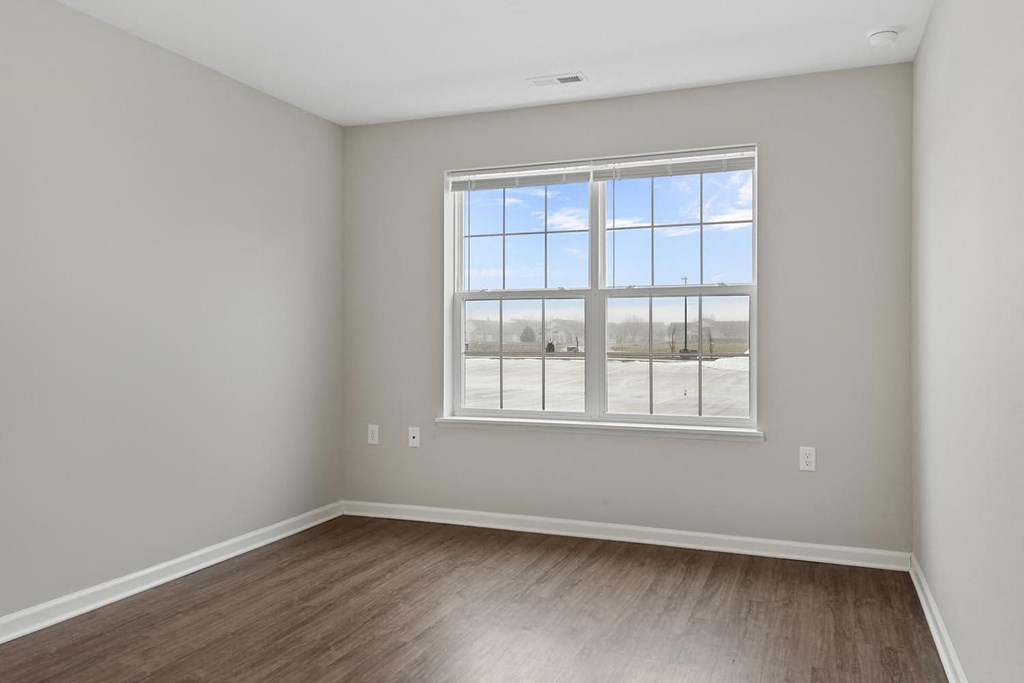 an empty room with a large window and wood floors