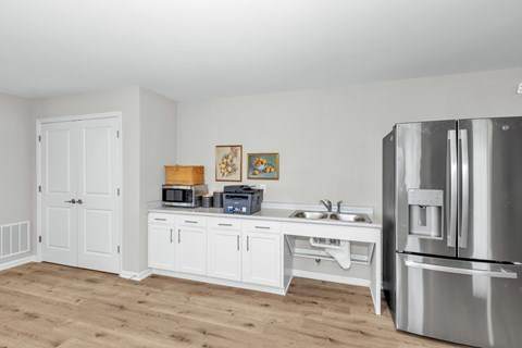 A kitchen with a refrigerator, microwave, and sink.