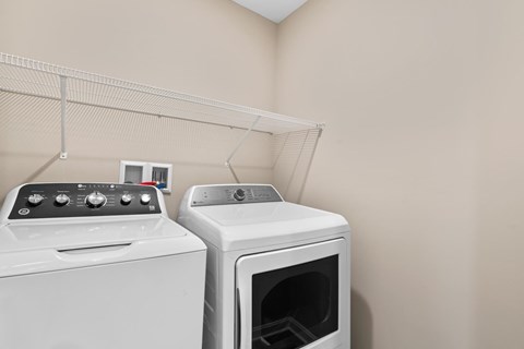 Two white appliances, a dryer and a washing machine, are in a room.