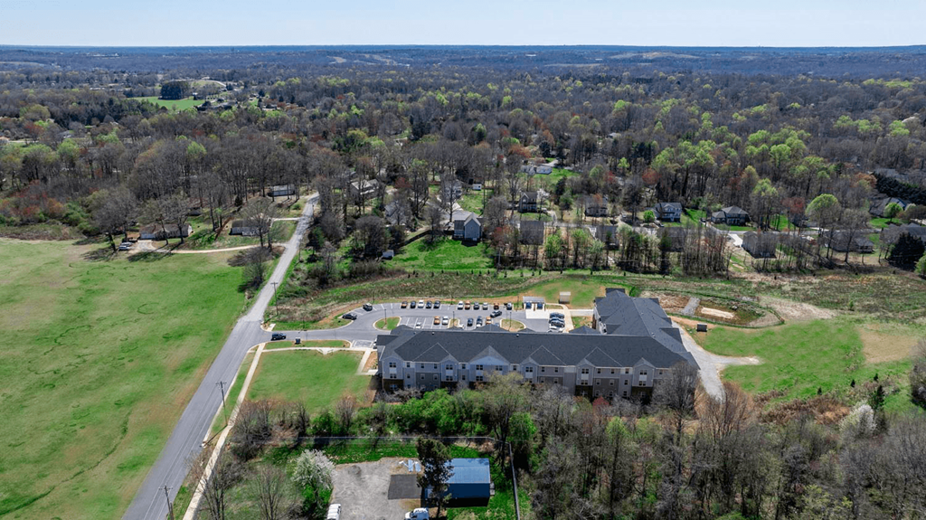 an aerial view of a house and a mansion with a green field and trees
