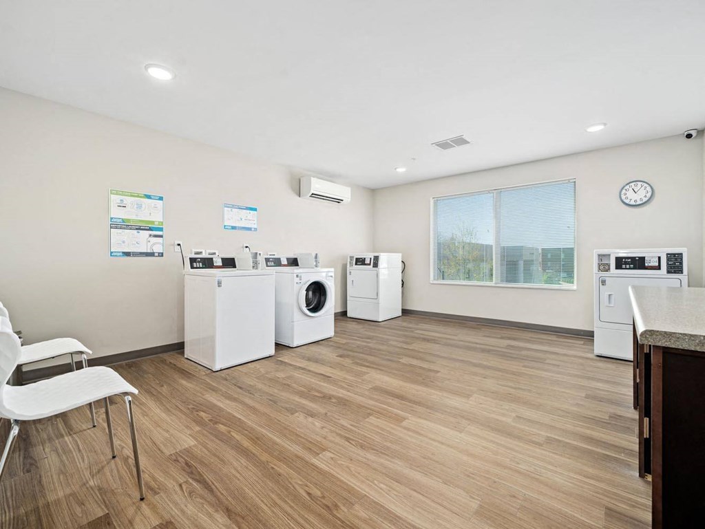 a laundry room with washer and dryers and a table with chairs