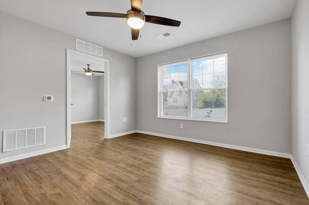 an empty living room with a ceiling fan and a window