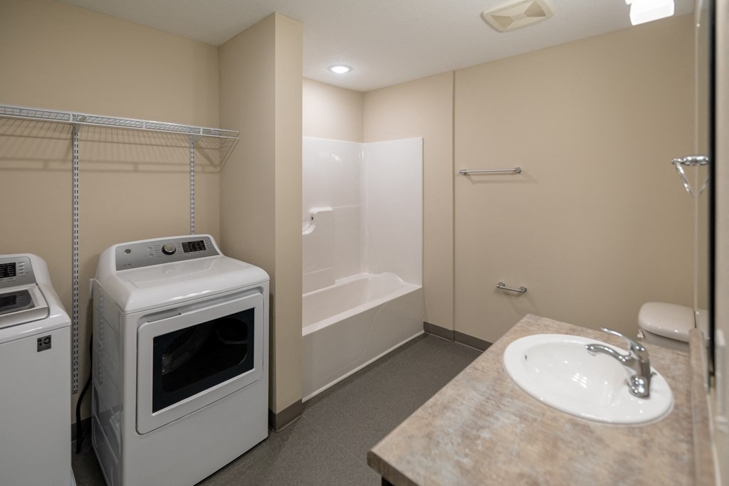a small bathroom with a washer and dryer and a shower and a sink