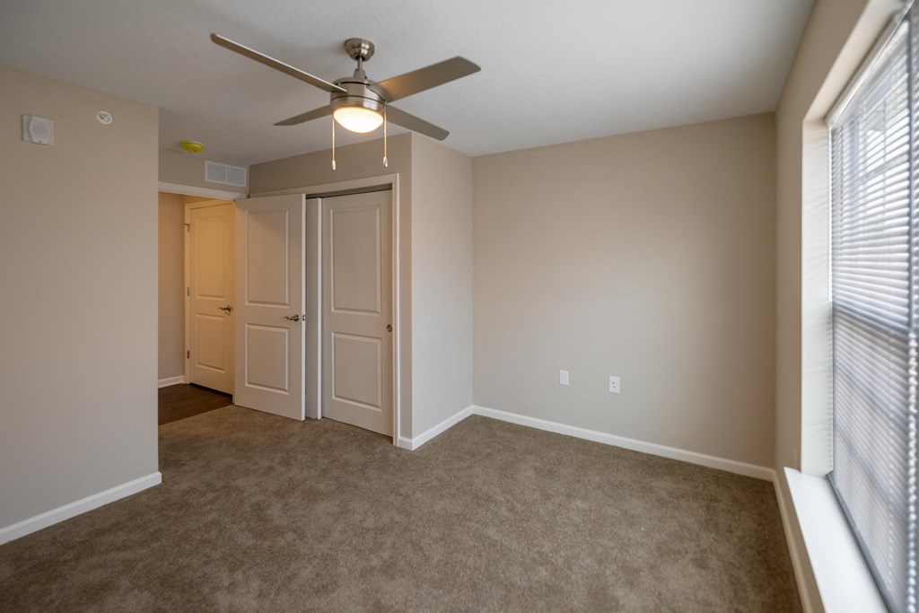 an empty living room with a ceiling fan and a closet