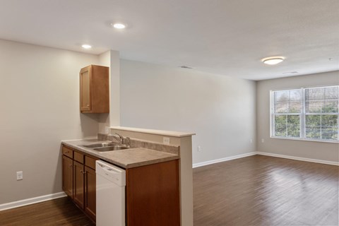 A kitchen with a white dishwasher and wooden cabinets.