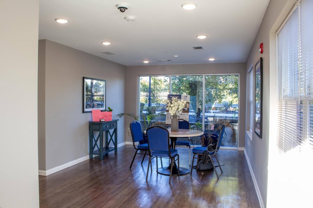 A room with a table and chairs with a view of trees outside.