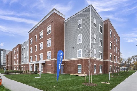 A modern brick building with a blue banner in front that says "Now Hiring".