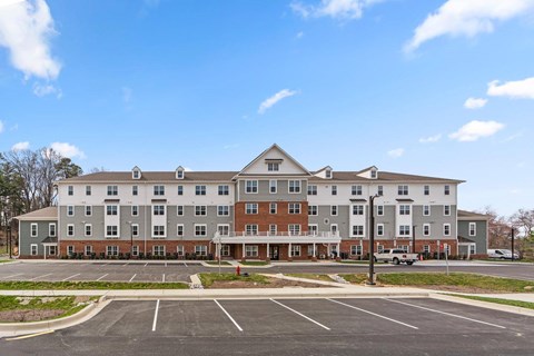 A large apartment complex with a parking lot in front.