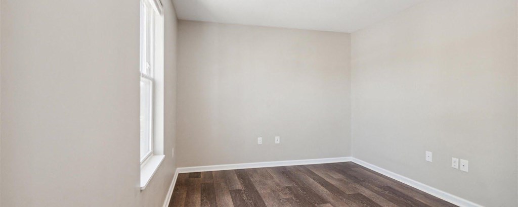 an empty room with hardwood floors and a window