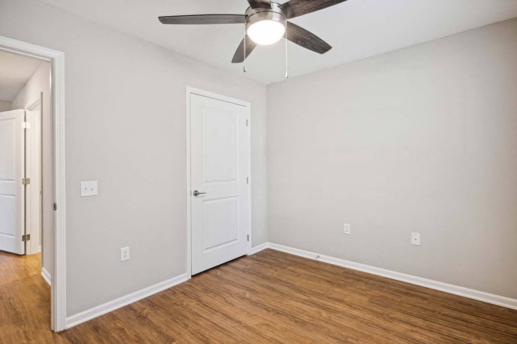 an empty bedroom with a ceiling fan and a door
