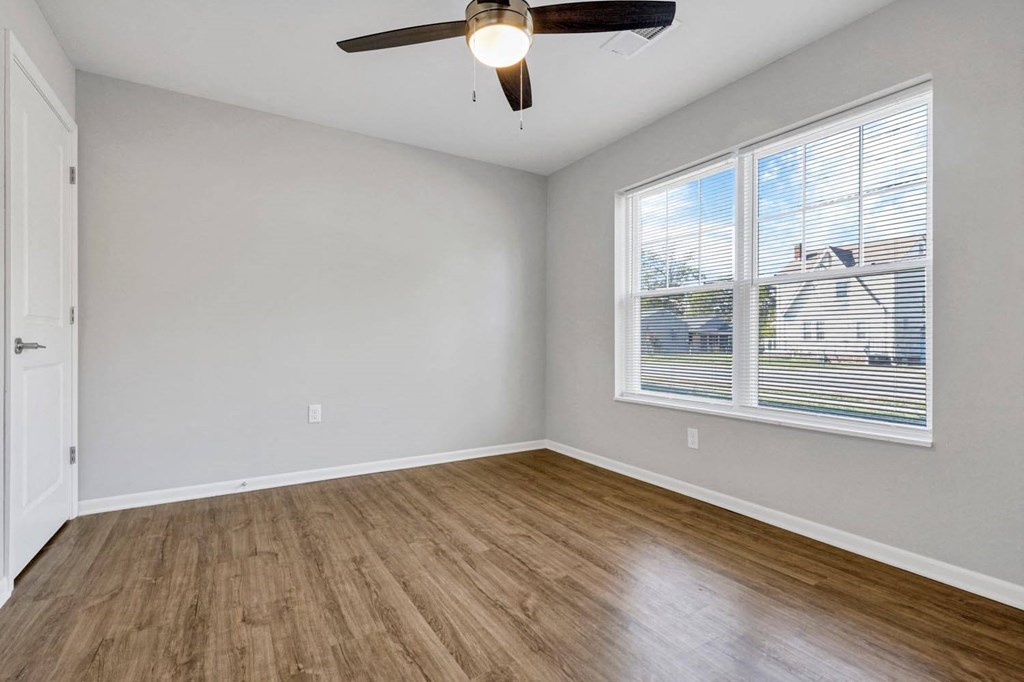 an empty living room with a large window and wooden floors