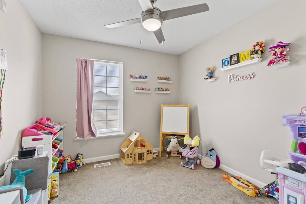 a bedroom with a ceiling fan and toys on the floor