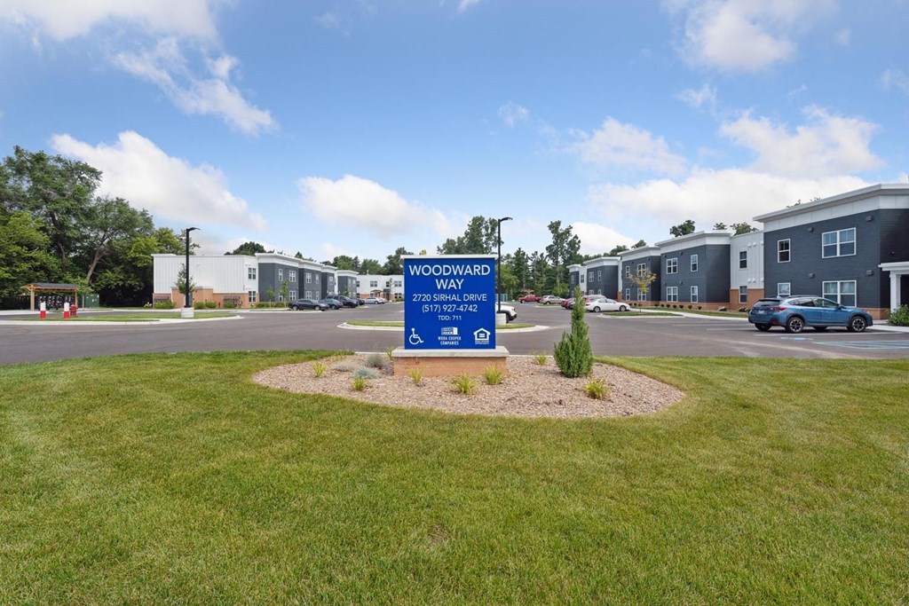 a sign that says woodland way in the middle of a grassy area