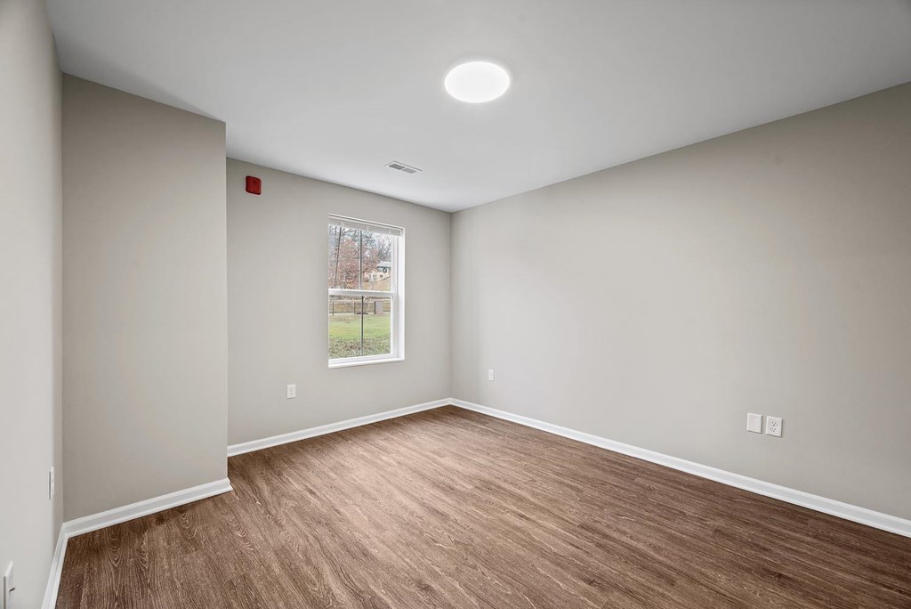 A room with a window and a wooden floor.