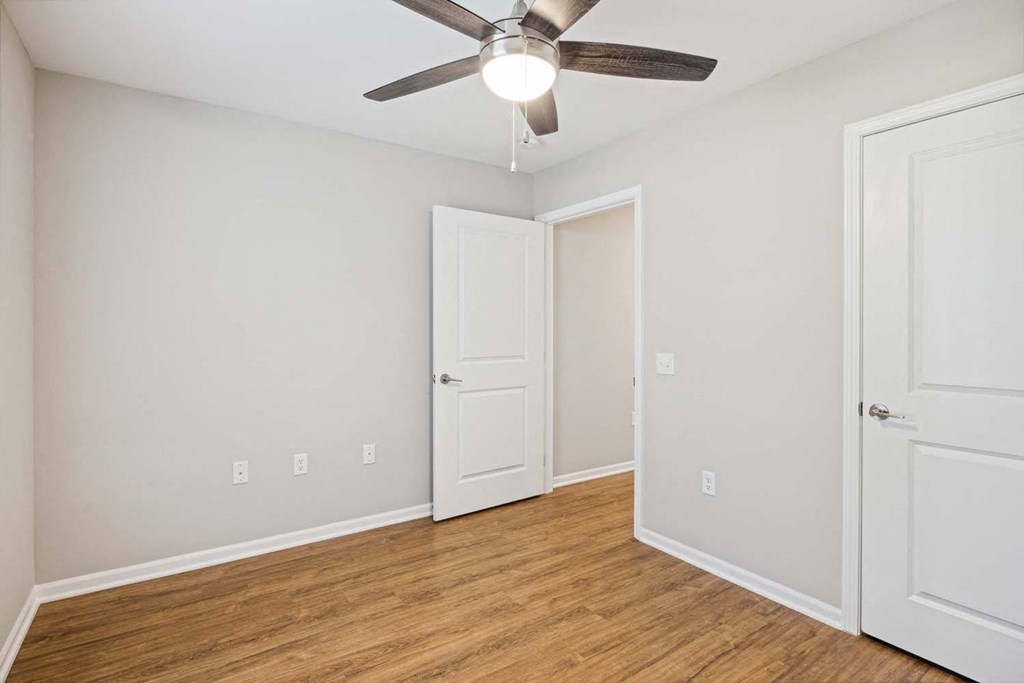 a bedroom with a ceiling fan and a door to a closet