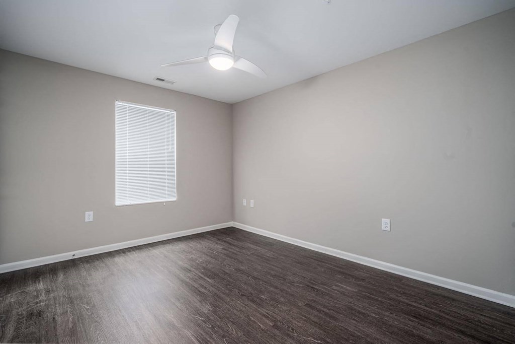 an empty living room with wood floors and a ceiling fan