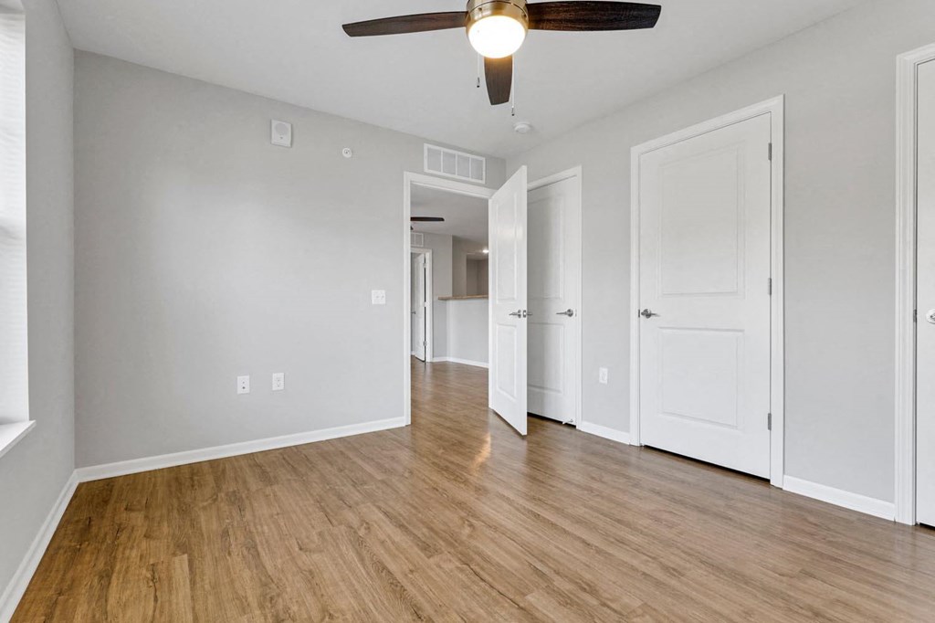 an empty living room with wood floors and a ceiling fan