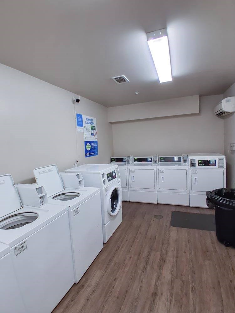 A row of white front load washing machines in a laundromat.