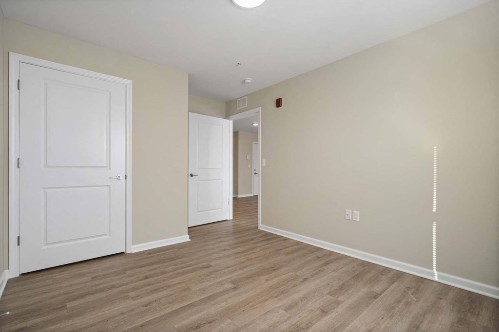 an empty living room with white doors and wood floors