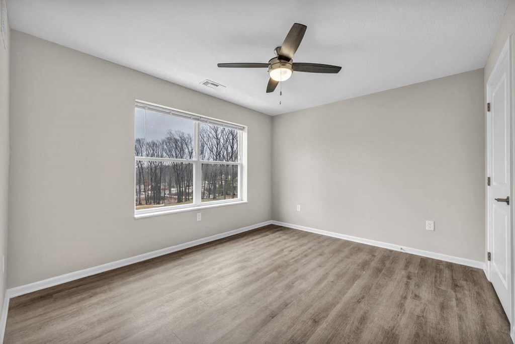 an empty living room with a window and a ceiling fan
