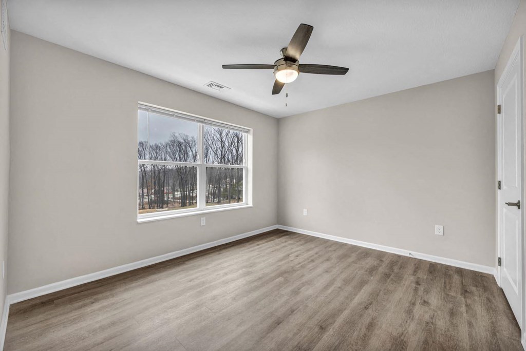 an empty living room with a window and a ceiling fan