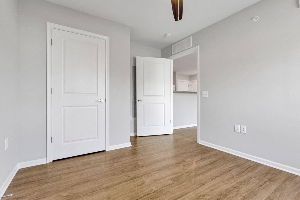 an empty living room with white doors and a wood floor