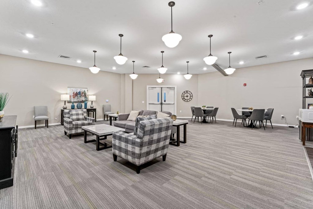 a community room with couches and chairs and tables and lights