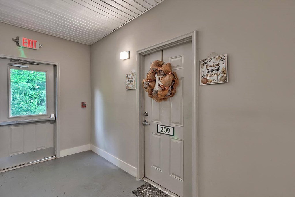 a white door with a teddy bear on it in a room with a window