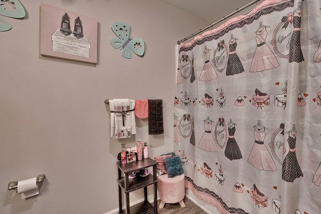 a dressing room with a shower curtain with dresses on it