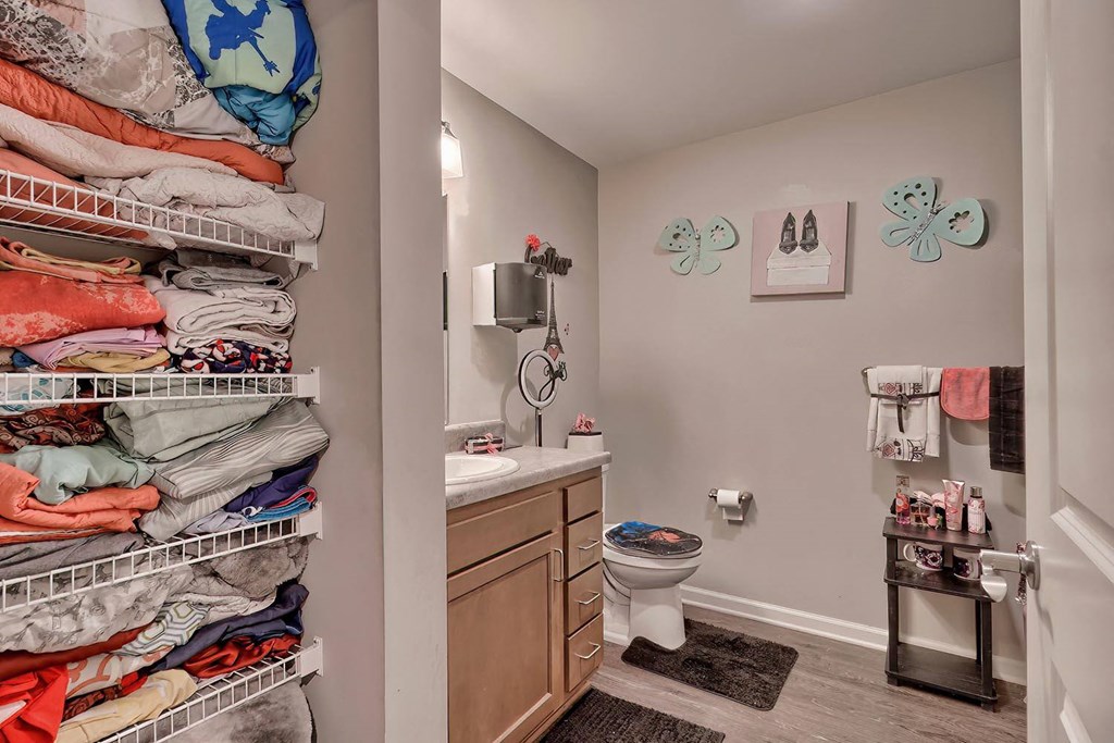 a bathroom with a closet full of clothes and a toilet