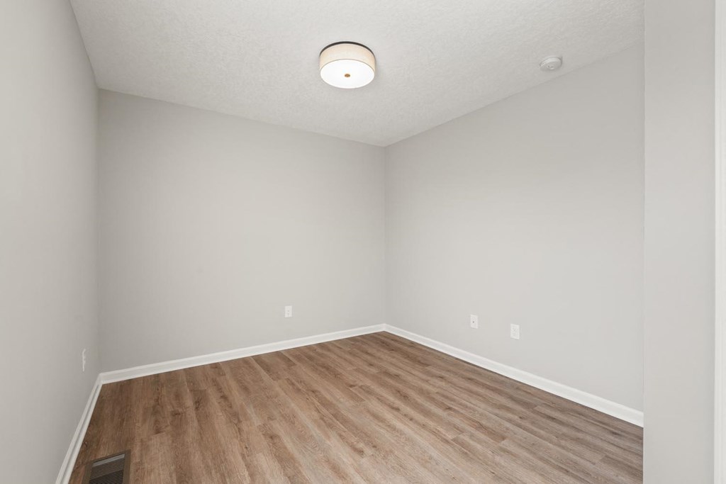 A room with a light on the ceiling and a wood floor.