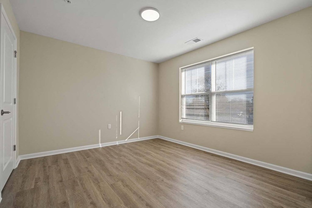 an empty living room with a large window and wooden floors