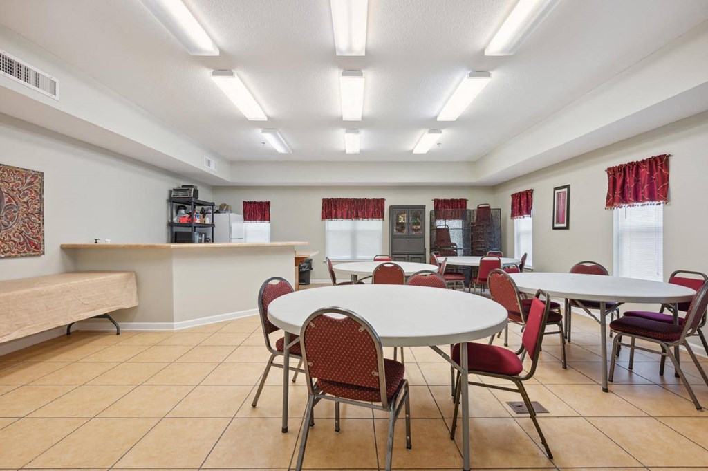 a community room with tables and chairs and a kitchen