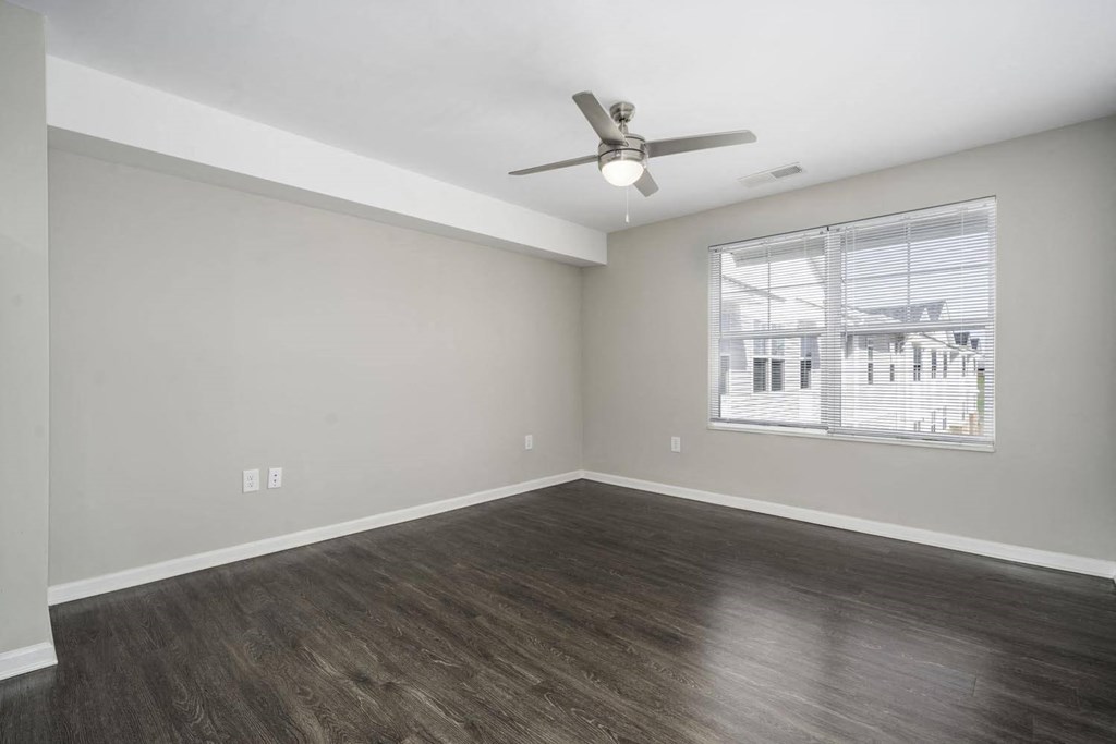an empty living room with a ceiling fan and a window