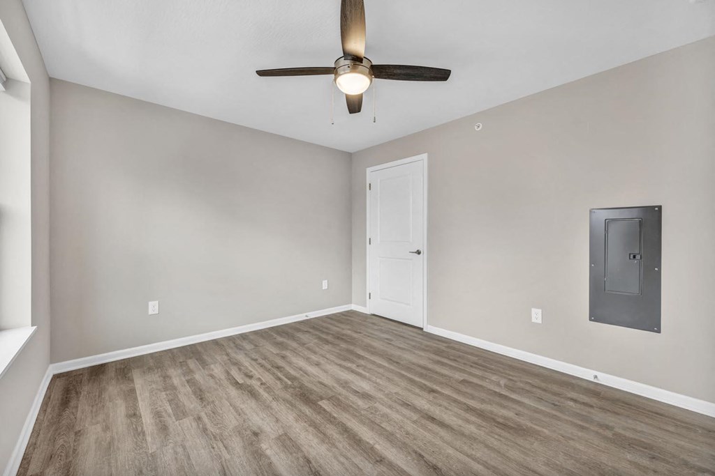 an empty living room with a ceiling fan and a door