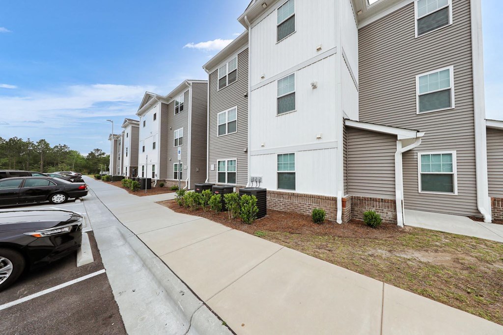 a row of apartment buildings with cars parked in front of them