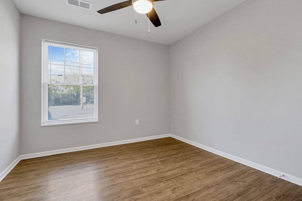an empty living room with wood floors and a window